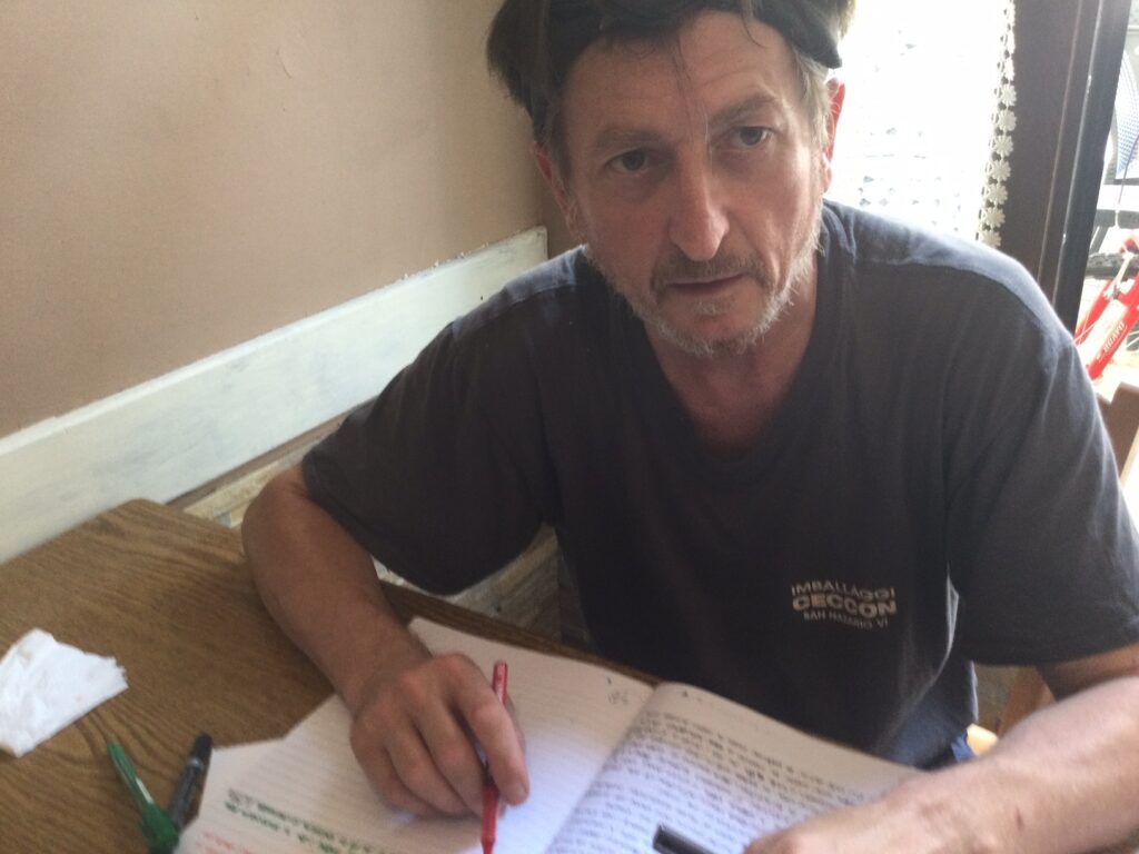 Foto di Diego seduto in un bar che sta scrivendo pagine di uno dei suoi libri